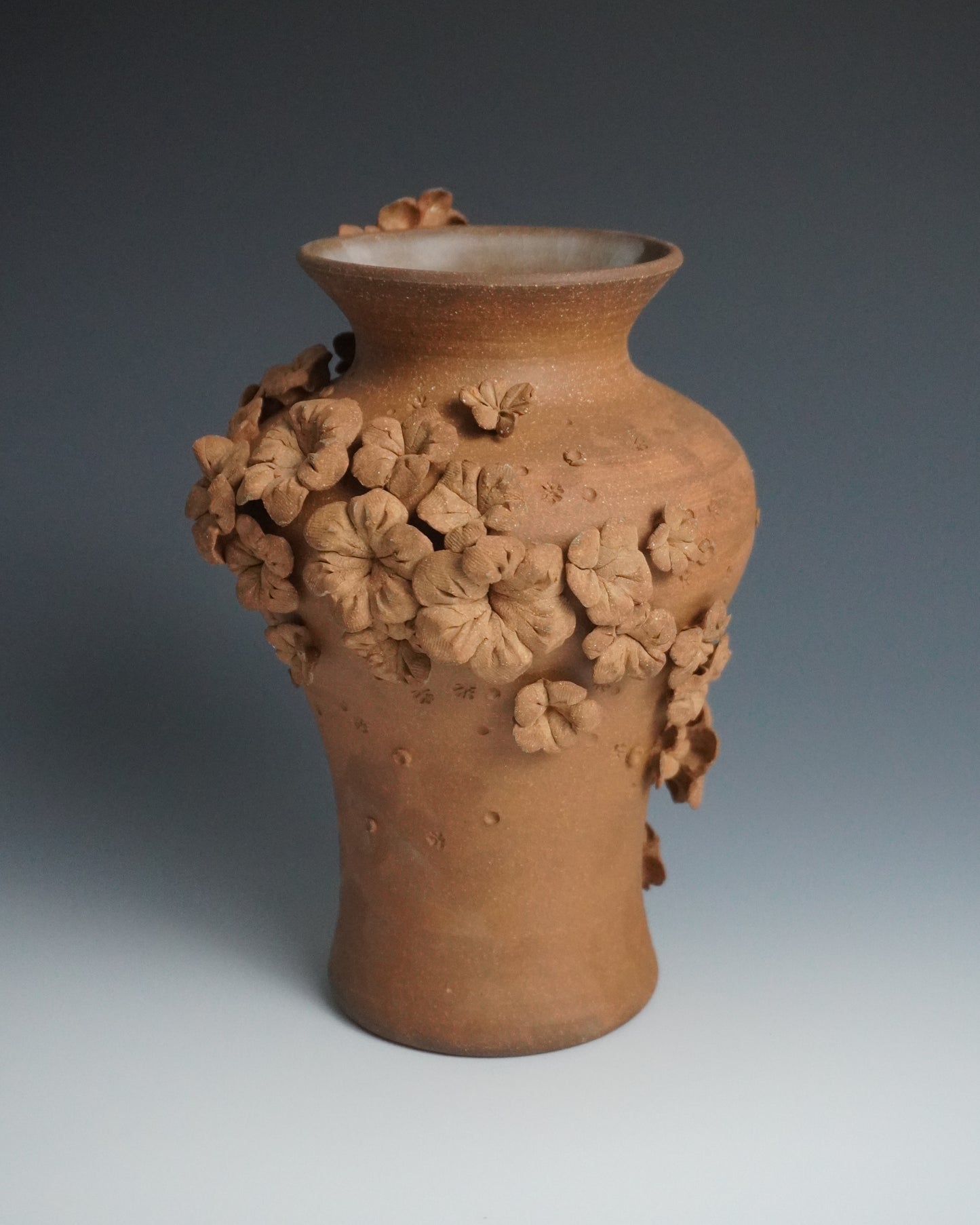 Terracotta vase with floral patterns on a gradient background