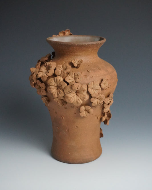 Terracotta vase with floral patterns on a gradient background