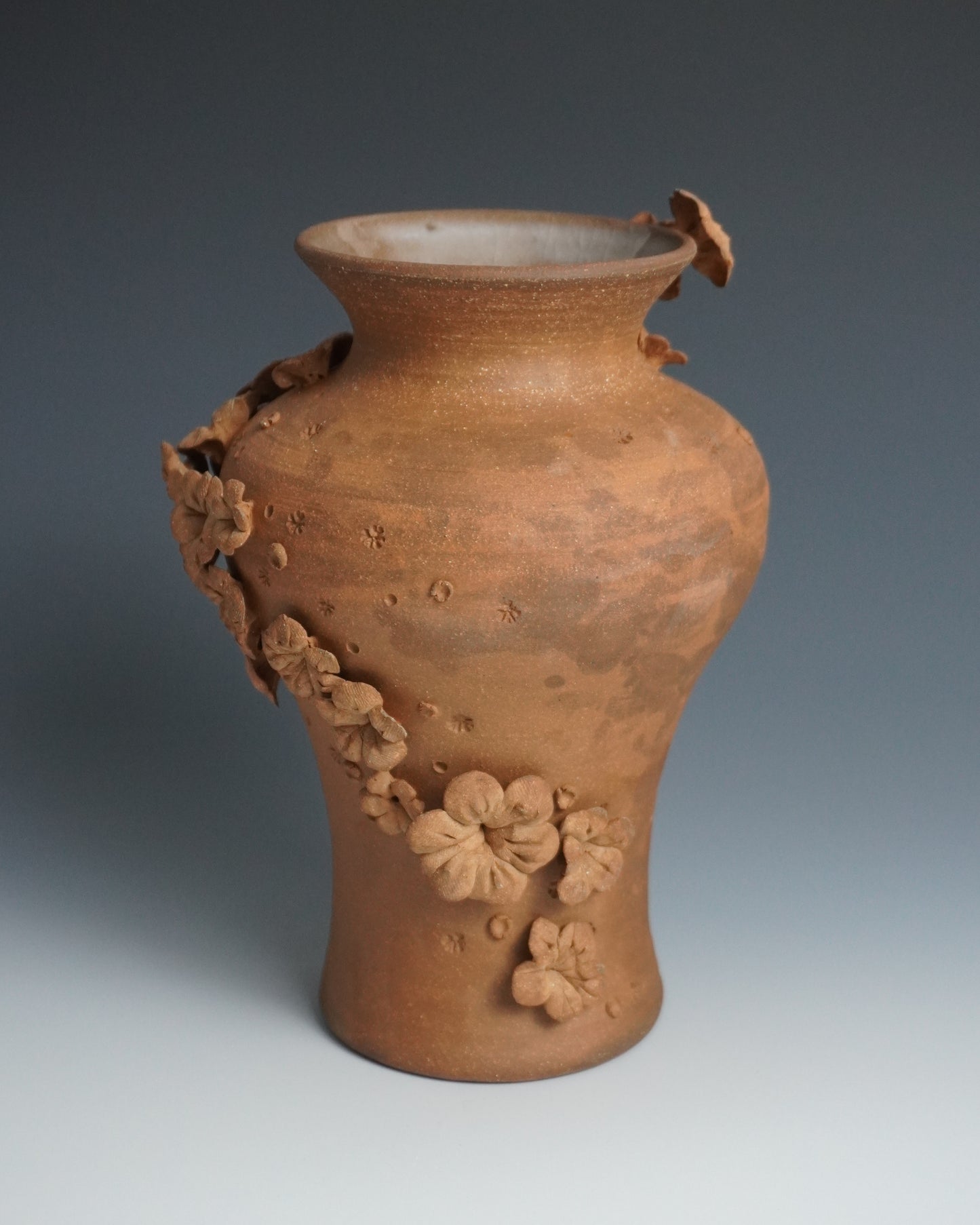 Terracotta vase with floral decorations on a gradient background