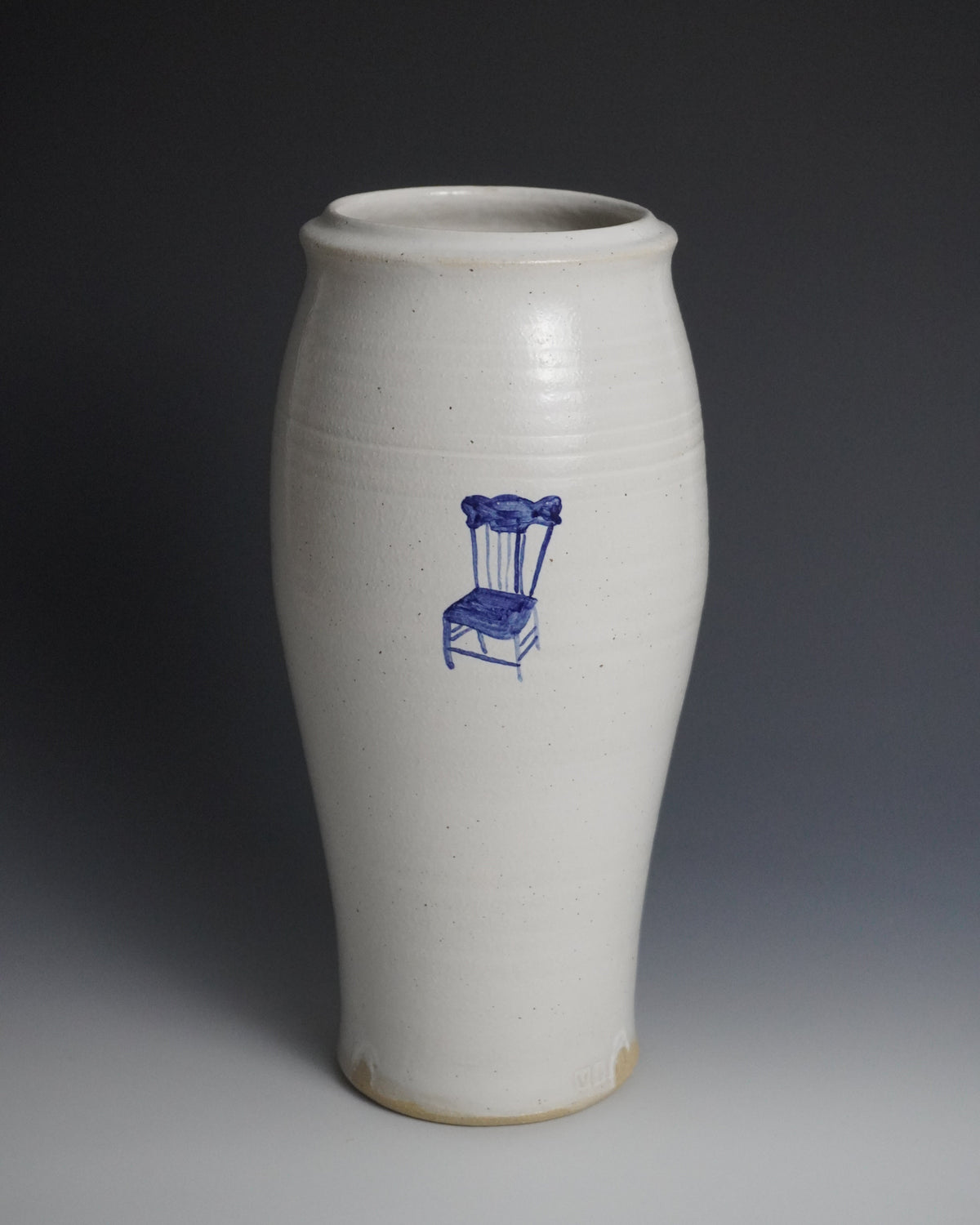 A tall, white ceramic vase with a blue line drawing of a chair on the front, set against a dark gray gradient background.